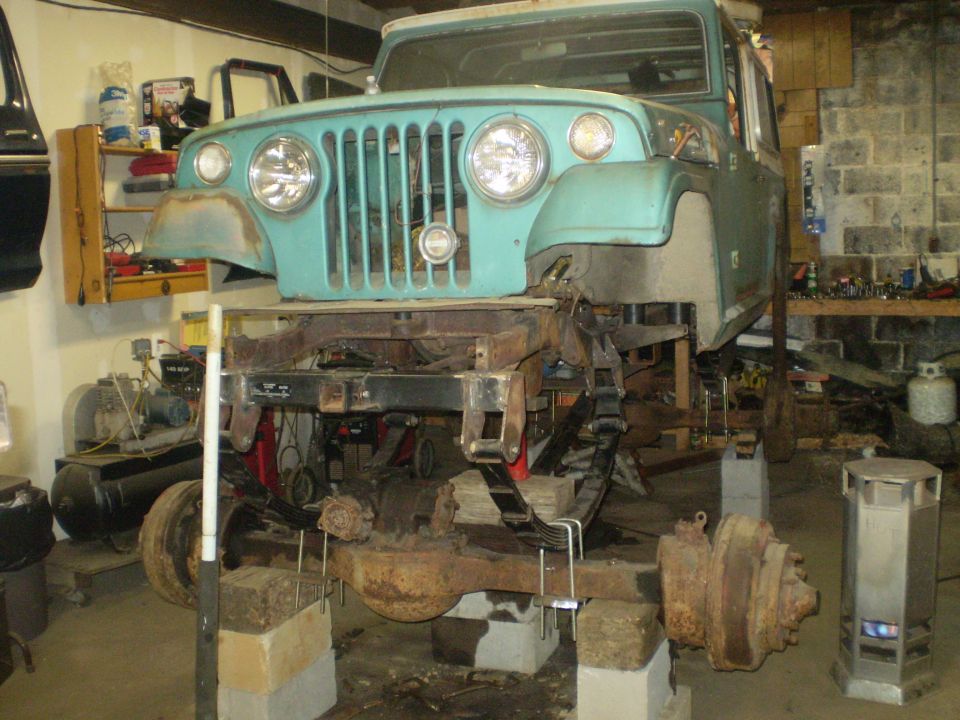 Teal Jeep body on a disassembled frame, front view