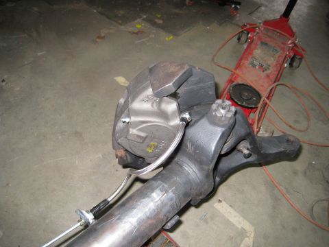 1996 Ford Bronco - Close-up view of a vehicle's axle and brake assembly, with a hydraulic jack visible in the background.