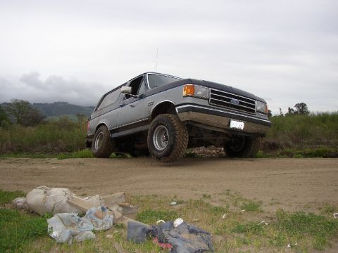 1989 Ford Bronco - This Ford Bronco is parked on a dirt road with debris in the foreground.