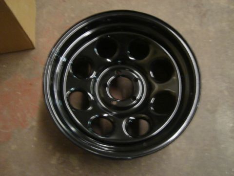 2000 Ford Crown Victoria - A black steel wheel with a polished lip and multiple circular cutouts is shown, with a SuperMotors watermark at the bottom.