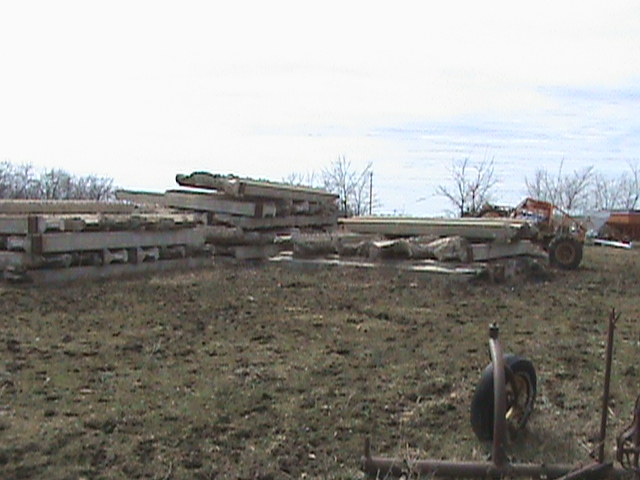 Stacked concrete beams and a forklift in a field