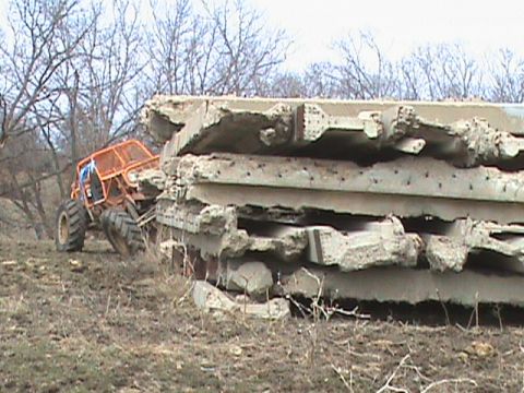 1973 Ford Bronco - An orange buggy navigates a rough terrain next to a stack of concrete debris.