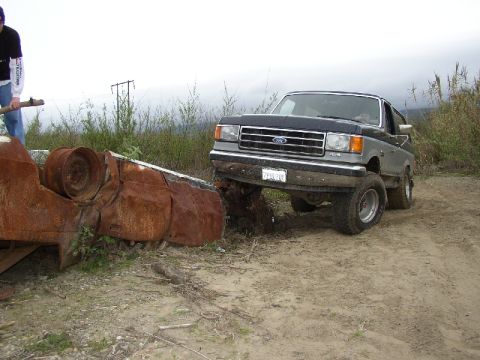 1989 Ford Bronco - This lifted 1987 Ford Bronco features a two-tone paint scheme and appears to be navigating rough terrain.