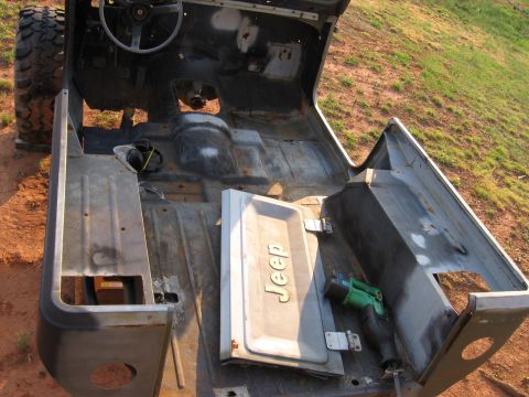 1980 Jeep CJ7 - The interior of a disassembled Jeep CJ is shown, with the body shell sitting outdoors on a dirt and grass surface.