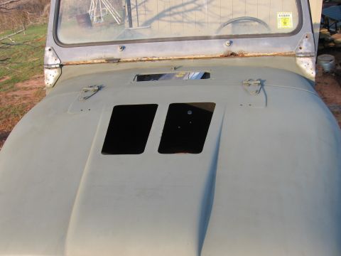 1980 Jeep CJ7 - The hood of a gray Jeep CJ7 shows two rectangular cutouts and a yellow sticker is visible on the windshield.