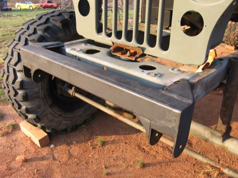 1980 Jeep CJ7 - The front bumper and grille of a 1980 Jeep CJ7 are visible, large off-road tires. Two other vehicles are in the background.
