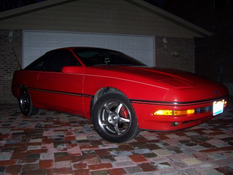 1989 Ford Probe - A red 1989 Ford Probe is parked on a brick driveway in front of a garage.