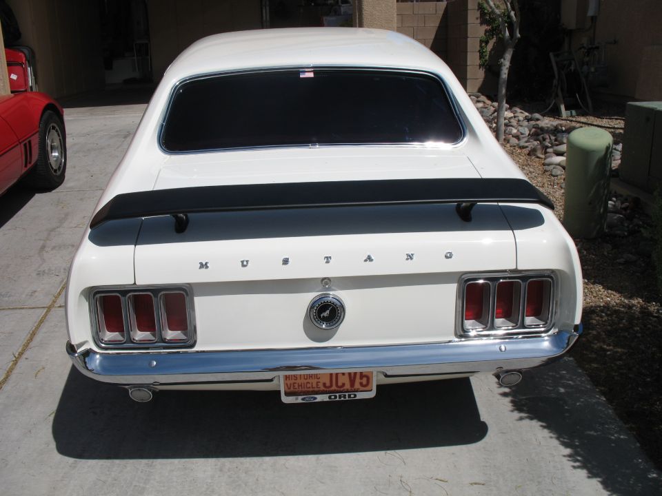 White 1970 Ford Mustang fastback rear view in a driveway