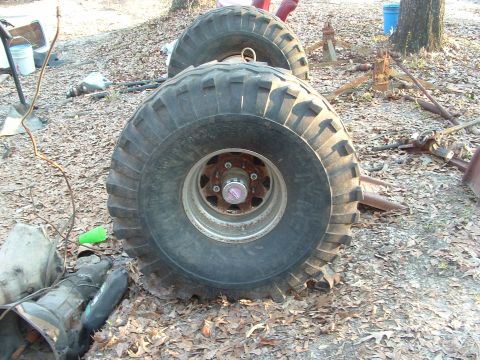 1979 Ford Bronco - Large off-road tires and a transmission are shown in a yard setting.