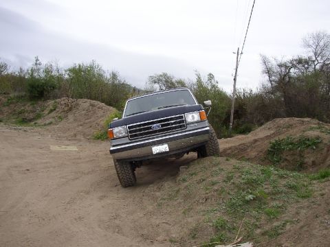 1989 Ford Bronco - A Ford F-Series truck navigates a dirt incline, its front grille and off-road capability.