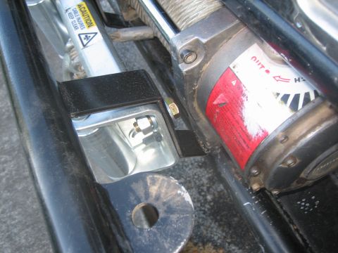 1995 Ford Bronco - A close-up view of a winch and its mounting bracket, a caution label regarding cable injuries.