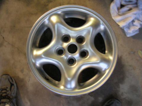 1999 Land Rover Discovery II - A single silver alloy wheel is shown from a top-down perspective on a concrete surface.