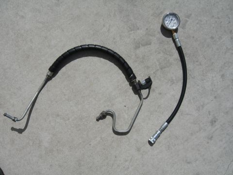 1997 Chevrolet C/K Pickup - A power steering hose and pressure gauge are laid out on a concrete surface, with the gauge showing a reading.