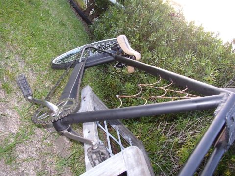 Bicycle frame with pedals and chainring lying on grass