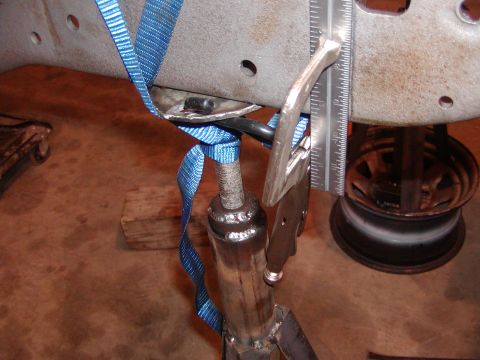 1991 Ford Bronco - Close-up of a vehicle frame section being supported by a jack and strap, with a ruler indicating a measurement.