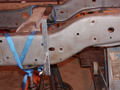1991 Ford Bronco - Measuring a section of a vehicle frame with a ruler and straps. The specific vehicle is not identifiable.