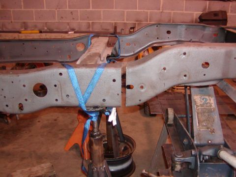 1991 Ford Bronco - Two sections of a vehicle frame are held up by jack stands and secured with blue straps.