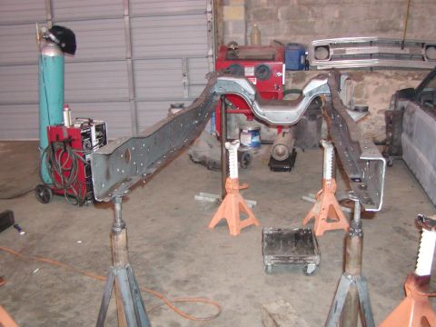1991 Ford Bronco - Vehicle frame undergoing repairs in a garage setting, with welding equipment nearby.