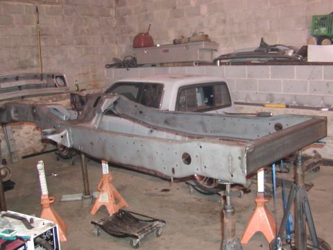 1991 Ford Bronco - The frame and chassis of a vehicle are visible, supported by jack stands in a workshop setting.