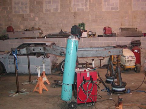 1991 Ford Bronco - Vehicle frame undergoing work in a garage setting, with various tools and equipment present.