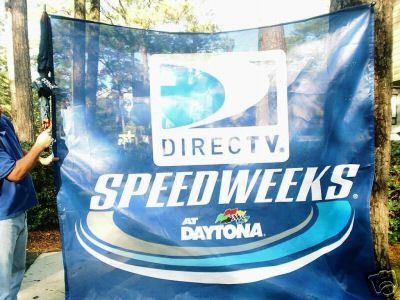 1993 Ford C-350 (Centurion Conversions) - A large blue banner advertising Directv Speedweeks at Daytona is displayed outdoors.