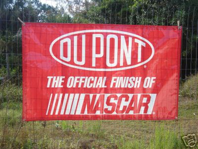 1993 Ford C-350 (Centurion Conversions) - A red banner advertising DuPont as the official finish of NASCAR is hung on a fence outdoors.