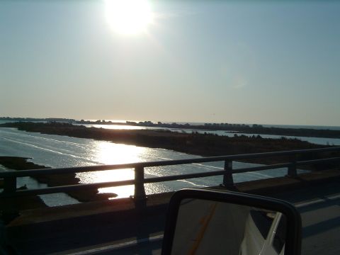 1979 Ford Ranchero - View from a vehicle traveling over a bridge, looking out at a sunlit waterway and distant land.