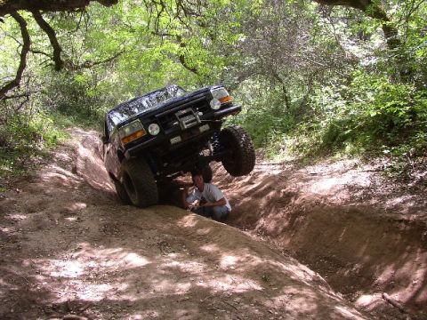 1989 Ford Bronco - A person works on a vehicle as it navigates a challenging off-road trail.