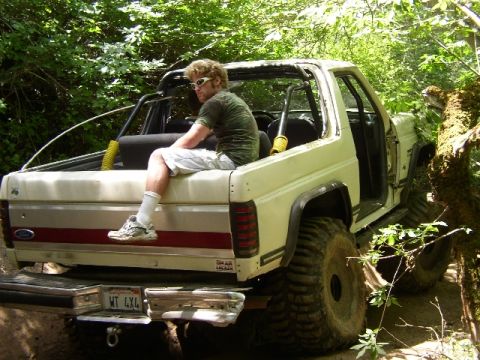 1989 Ford Bronco - This 1989 Ford Bronco is shown in a rear view, equipped with off-road tires and a man relaxing in the open bed.