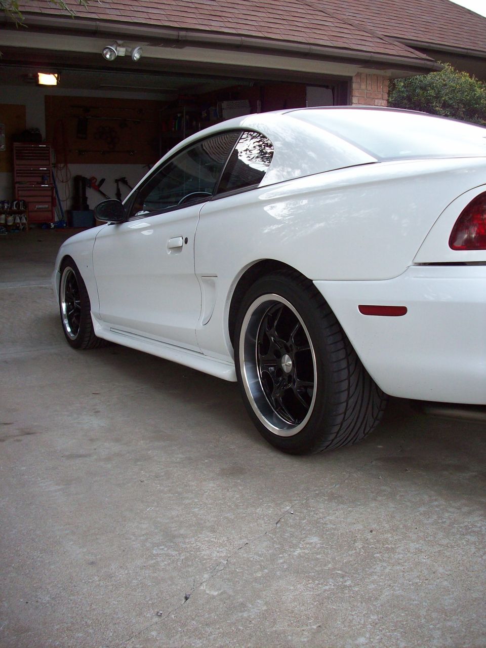 White 1997 Ford Mustang coupe, rear 3/4 view, black rims