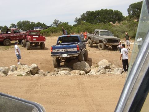 1989 Ford Bronco - Several off-road trucks navigate a rocky terrain course.