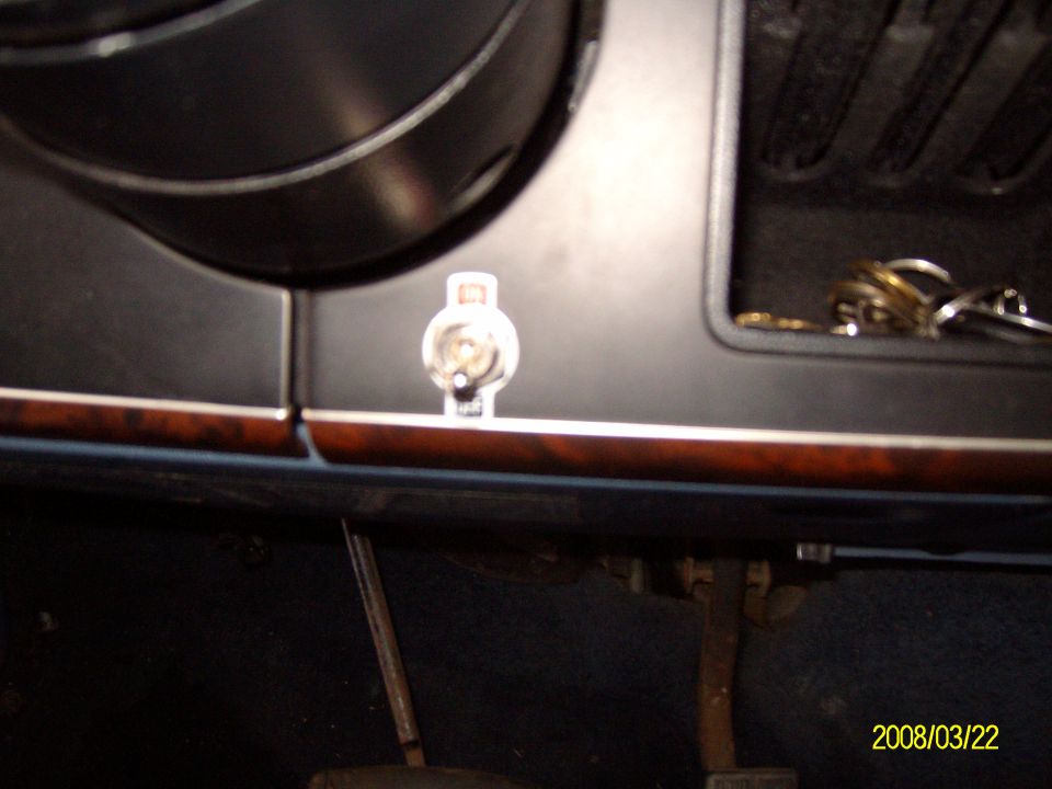 Dashboard interior with wood trim, a keyhole, and a set of keys in a compartment