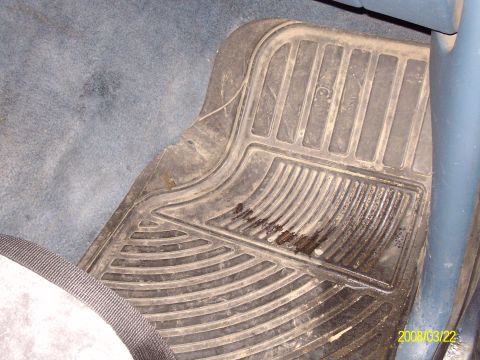 1988 Ford Bronco - The driver's side floor mat shows signs of wear and tear, with dirt and liquid stains.