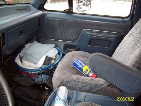 1988 Ford Bronco - Interior of a blue-trimmed Ford truck looking across to the passenger side, showing the door panel with round speaker and pull handle, a gr…