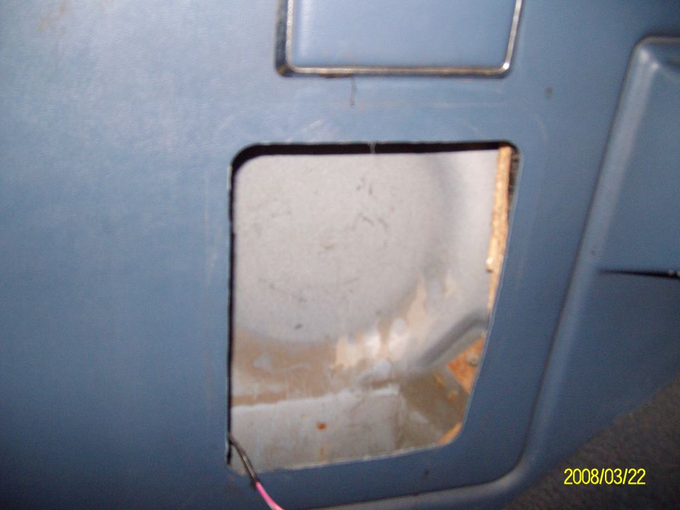 Square speaker hole cut in blue interior panel with wiring hanging out