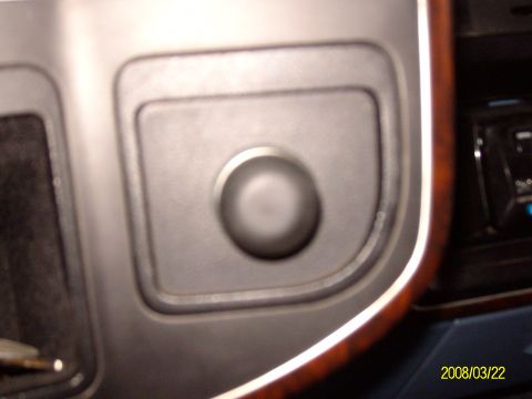 1988 Ford Bronco - A close-up view of a button on the dashboard of a vehicle, surrounded by wood trim.
