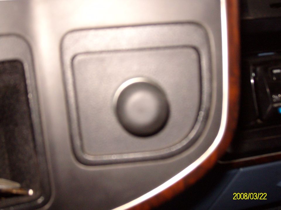 Close-up of a dark interior dashboard button with wood trim