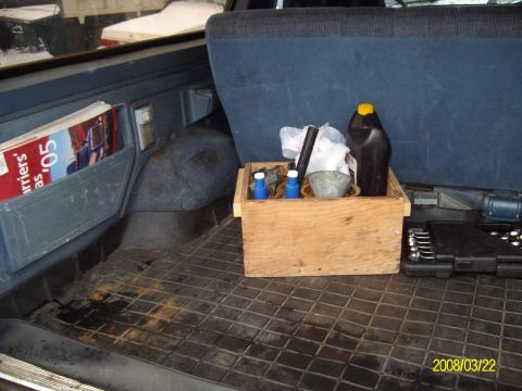 1988 Ford Bronco - Rear cargo area behind the driver-side rear quarter of a truck-based SUV, shot down onto a black rubber floor mat with blue trim panels and…