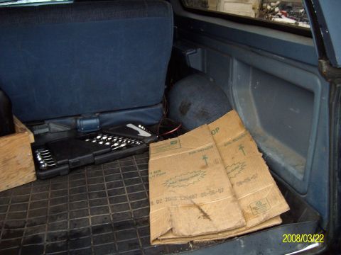1988 Ford Bronco - The interior cargo area of a vehicle contains a tool case and cardboard boxes on a rubber mat.