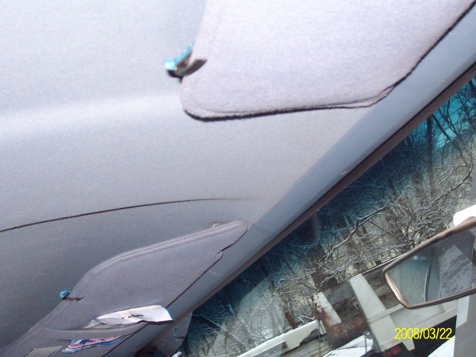 Gray cloth headliner and sun visors seen from inside, windshield at right