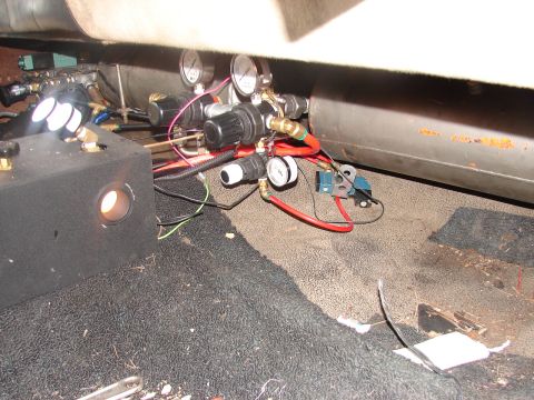 1973 Ford Ranchero - Onboard air system plumbing installed at floor level behind a seat, with a horizontal air tank, two round pressure gauges, pressure regulat…
