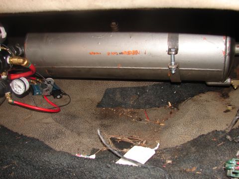 1973 Ford Ranchero - A silver cylindrical compressed-air tank is strap-mounted over black trunk carpet, plumbed to a pressure gauge, brass fittings and red air…