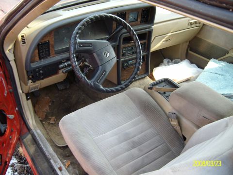 1986 Mercury Cougar - The interior of a car shows tan seats and a wood-grain dashboard with a black steering wheel.