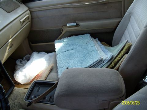 1986 Mercury Cougar - Interior view of a car with several rugs piled on the passenger seat.