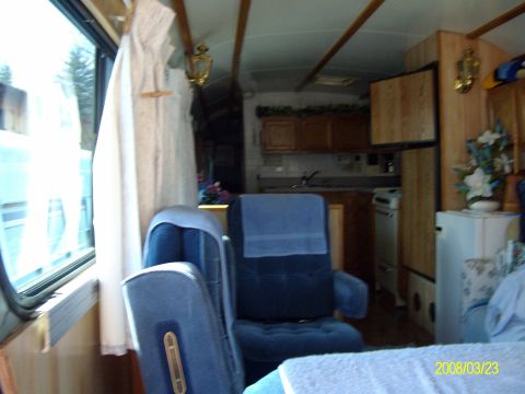 1988 Ford Bronco - Interior of a converted bus or motorhome looking rearward from behind two blue cloth captain's chairs, dated 03/23/2008. The living area ha…