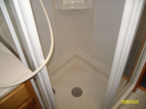 1988 Ford Bronco - Interior view of an RV shower stall, showing the shower curtain and floor drain.