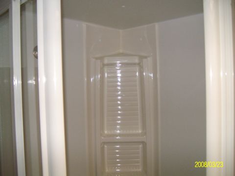 1988 Ford Bronco - The interior of a shower stall is shown, white walls and a built-in shelf.