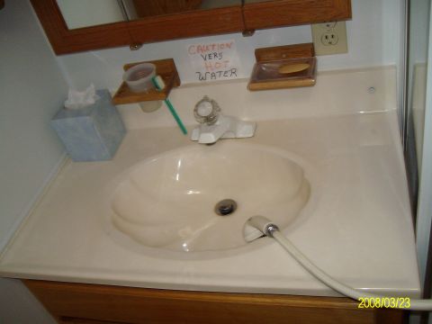 1988 Ford Bronco - A bathroom sink area with a faucet, soap, tissues, and a warning sign about hot water.