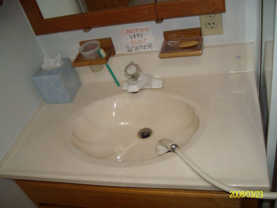 Bathroom sink with a tissue box, soap dish, and a 'CAUTION VERY HOT WATER' sign