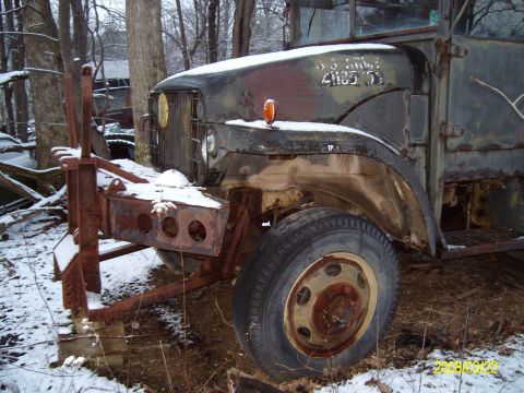 1988 Ford Bronco - This old military truck is parked outside in the snow, showing its front end and tire.